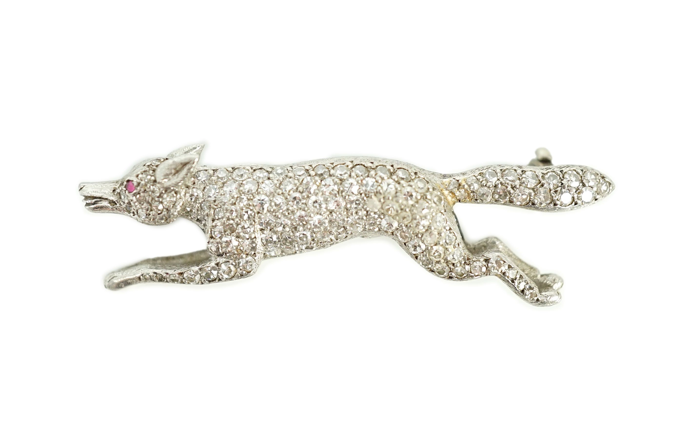 A Victorian style white gold, diamond encrusted and cabochon garnet set brooch, modelled as a running fox